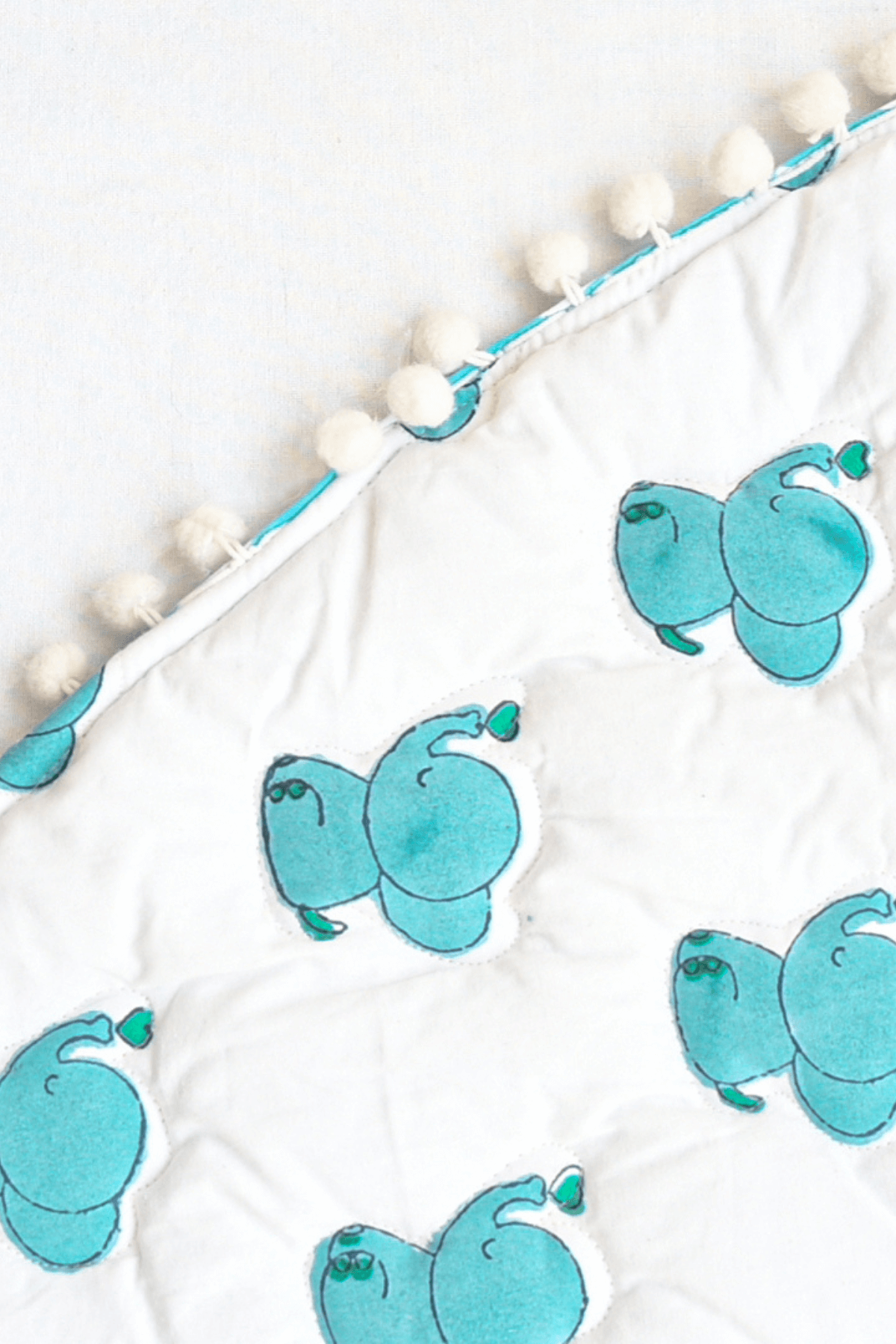 Edge detail of blue elephant cotton baby playmat showing stitching and padding