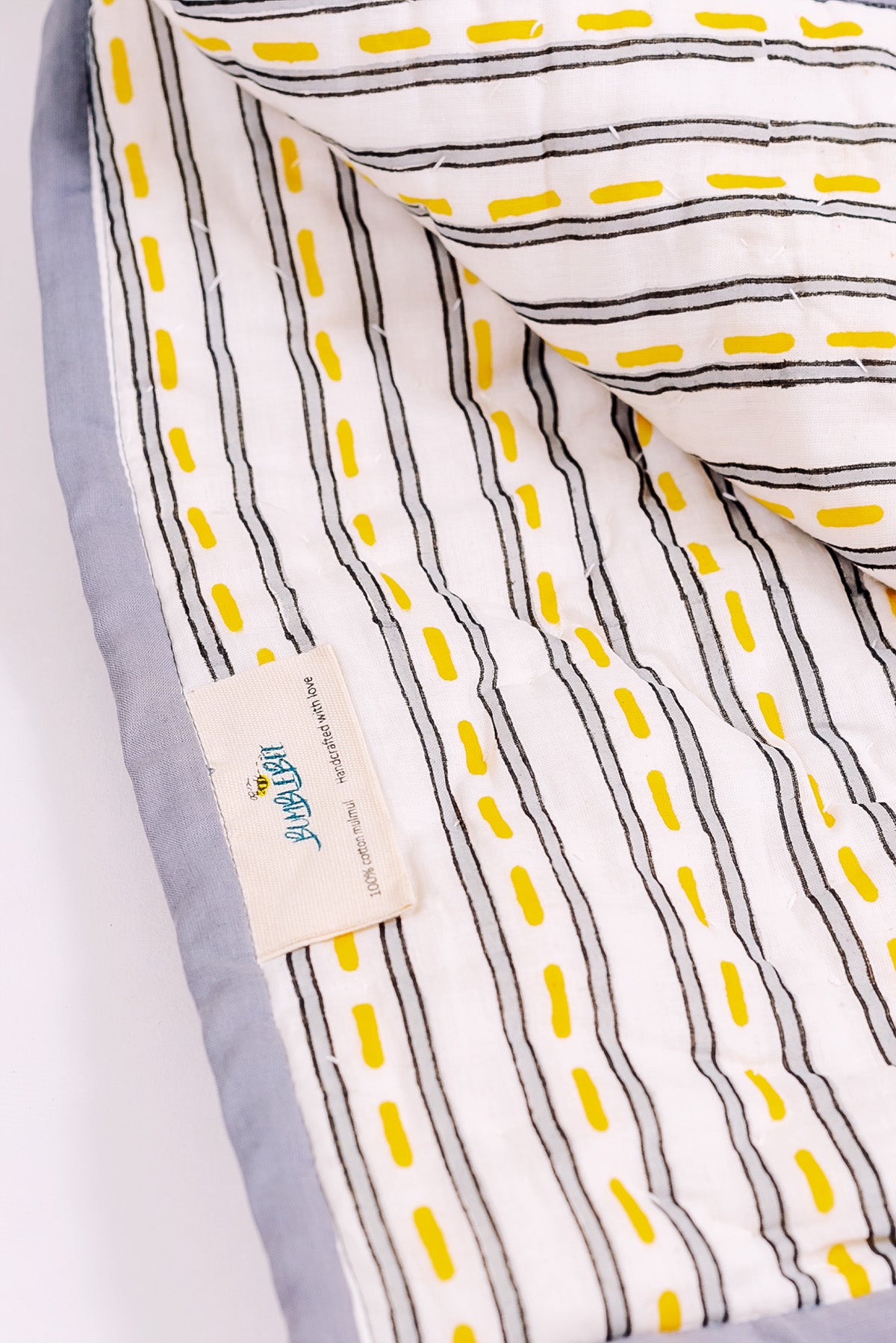 Close-up of hand block printed road stripe reverse on cotton mulmul quilt with Bumblebee label and grey border