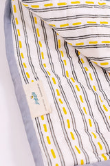 Close-up of hand block printed road stripe reverse on cotton mulmul quilt with Bumblebee label and grey border