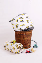 Construction truck print mulmul  quilt rolled beside matching cot bumper on a wicker basket with toy trucks