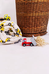 Rolled hand block printed cotton mulmul baby quilt with yellow construction truck print, styled with toy trucks