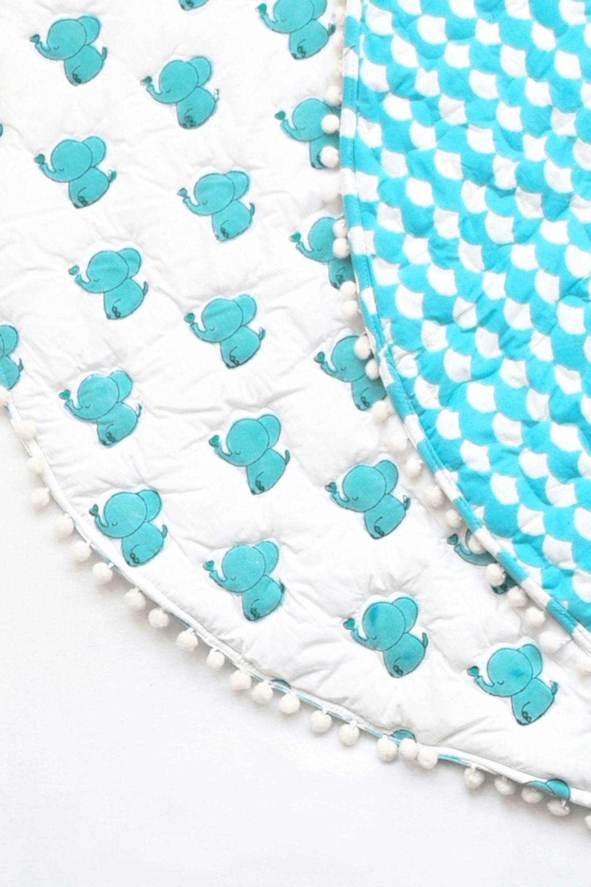 Folded blue elephant print cotton playmat showing extra padding and reversible print