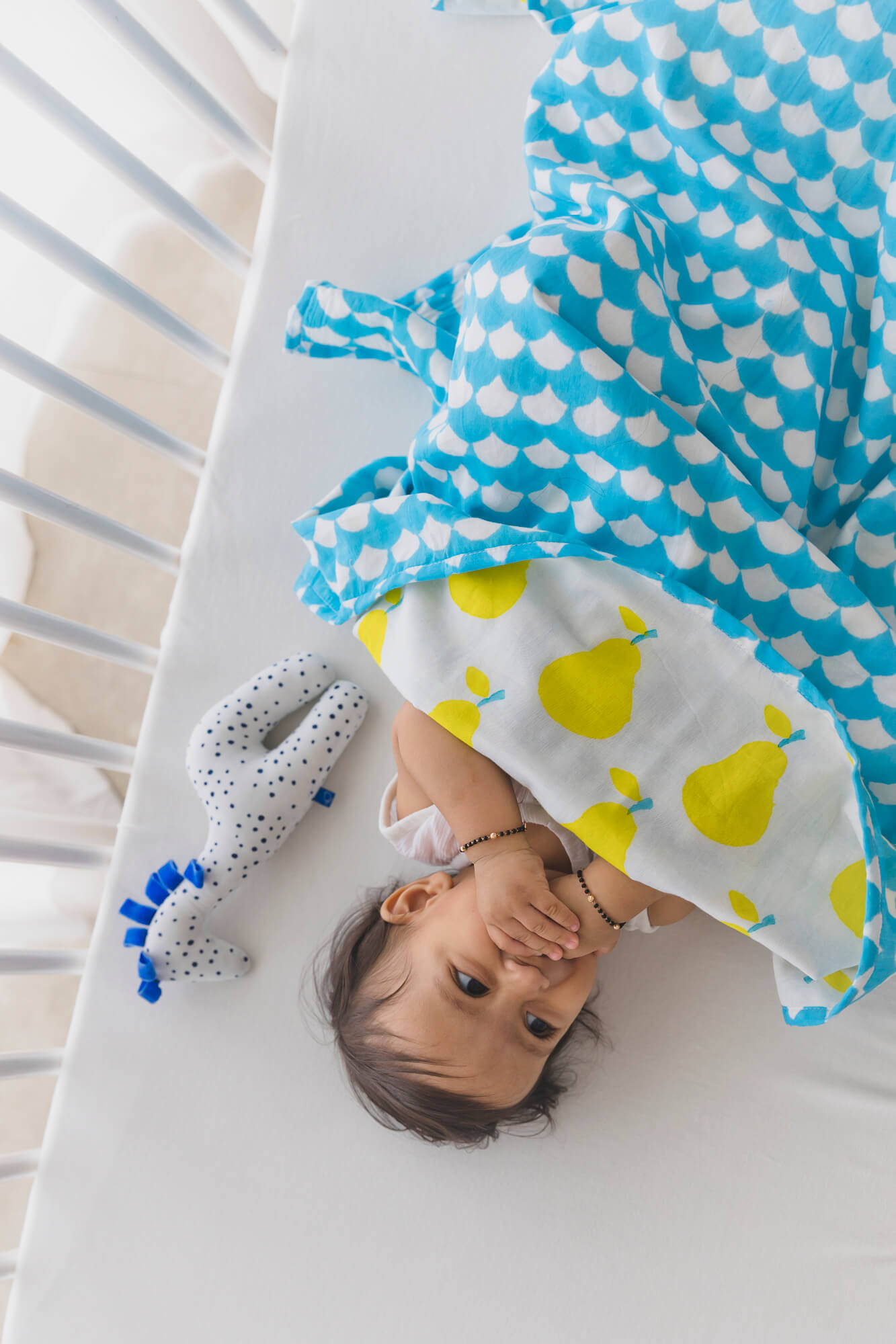 Infant in his crib with a yellow pear dohar