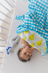 Infant in his crib with a yellow pear dohar